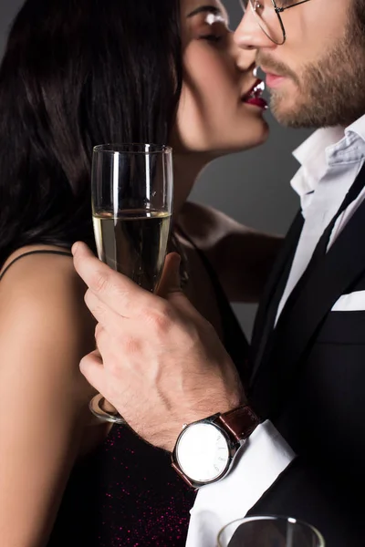 Abgeschnittene Ansicht eines Paares, das ein Glas Champagner hält und sich am Valentinstag küssen wird, isoliert auf grau — Stockfoto