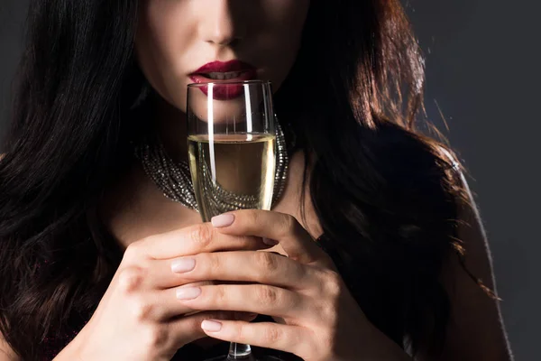 Обрезанный вид девушки, держащей бокал шампанского, изолированной на сером — стоковое фото