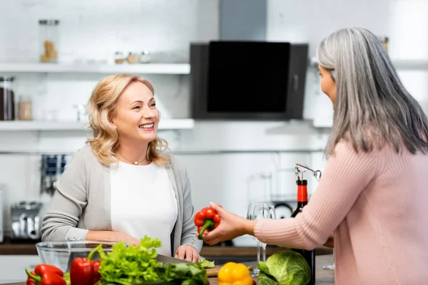 Femme souriante cuisine et parler avec son ami avec poivron — Photo de stock