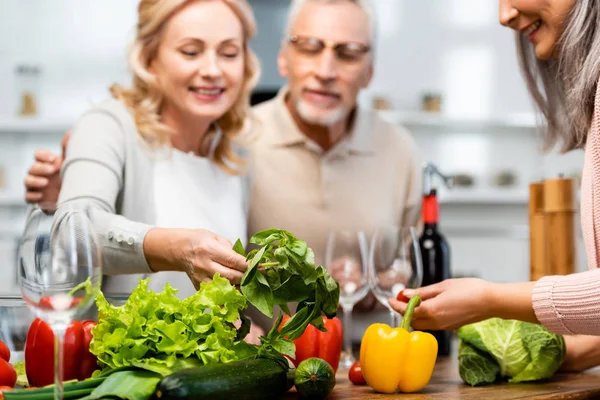 Foyer sélectif d'amis souriants regardant le basilic dans la cuisine — Photo de stock