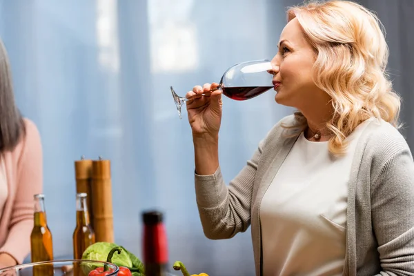 Vista lateral de la atractiva mujer bebiendo vino de copa de vino - foto de stock