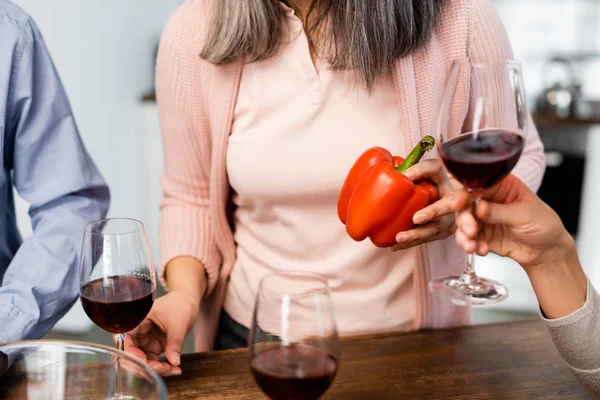 Cropped view of women holding bell pepper and wine glass — Stock Photo