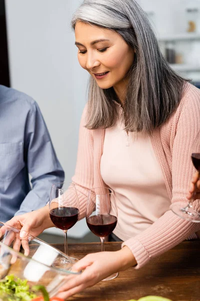 Selektiver Fokus lächelnder Asiatinnen beim Anblick einer Schüssel mit geschnittenem Salat — Stockfoto