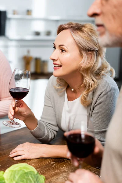 Messa a fuoco selettiva di attraente e sorridente donna in possesso di bicchiere di vino — Foto stock