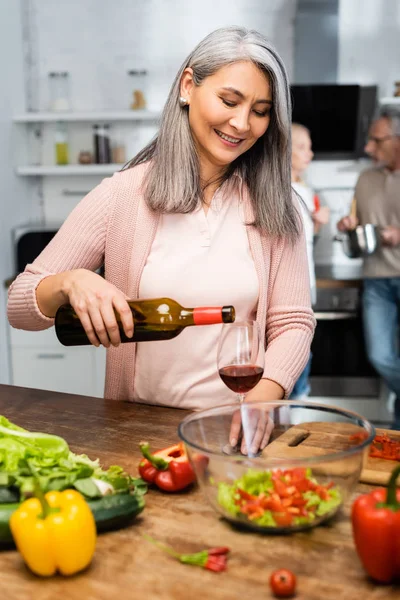 Selective focus of smiling asian woman pouring wine to glass — Stock Photo