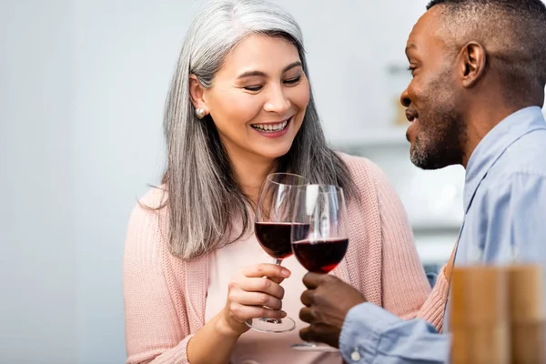 Selektiver Fokus lächelnder multikultureller Freunde, die mit Weingläsern klirren — Stockfoto