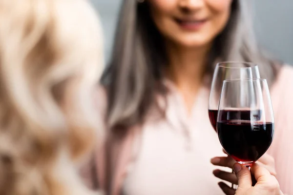 Vista recortada de amigos sonrientes tintineando con copas de vino - foto de stock