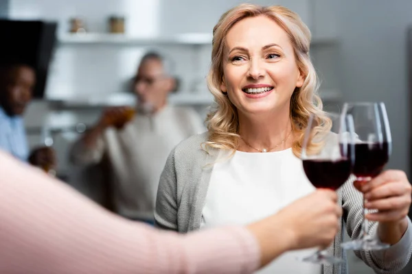 Cropped view of woman clinking with smiling and attractive friend — Stock Photo