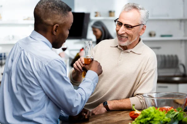 Africano americano uomo clinking con la sua sorridente amico in cucina — Foto stock