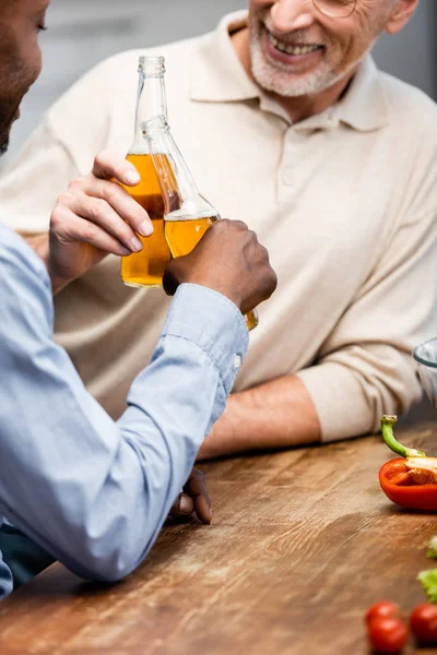 Cropped view of african american man clinking with his smiling friend in kitchen — Stock Photo