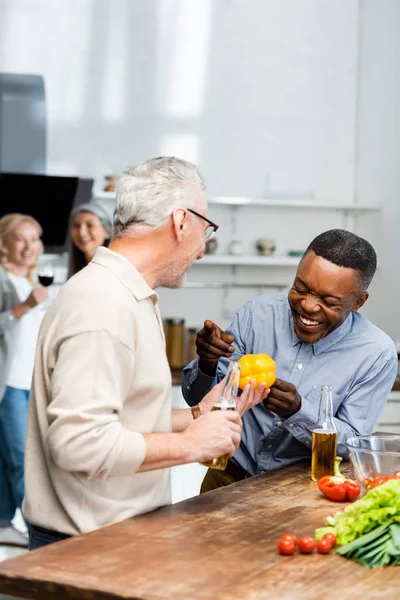 Sorridente afro-americano apontando com seu amigo com pimentão — Fotografia de Stock