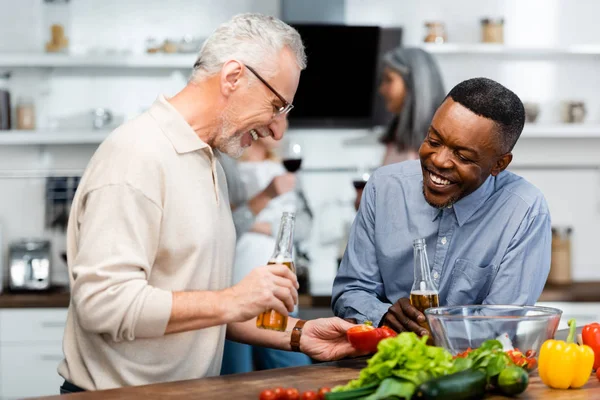 Sonriente afroamericano hombre y su amigo mirando corte pimiento - foto de stock