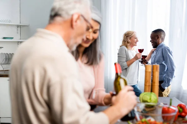 Selektiver Fokus eines afrikanisch-amerikanischen Mannes im Gespräch mit einem lächelnden Freund in der Küche — Stockfoto