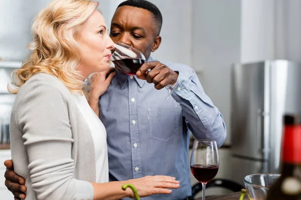 Foco seletivo do homem afro-americano dando copo de vinho ao amigo na cozinha — Fotografia de Stock