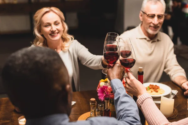Selektiver Fokus lächelnder multikultureller Freunde beim Abendessen — Stockfoto