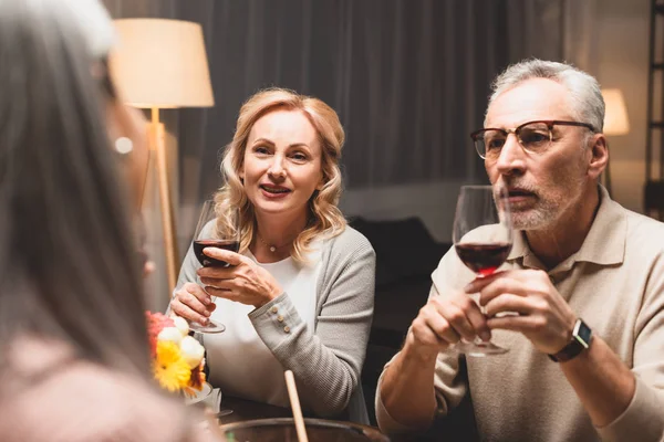 Selektiver Fokus lächelnder Frauen und Männer im Gespräch mit Freunden beim Abendessen — Stockfoto