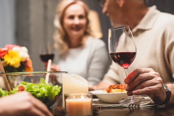 Selective focus of man holding wine glass and talking with smiling woman during dinner — Stock Photo