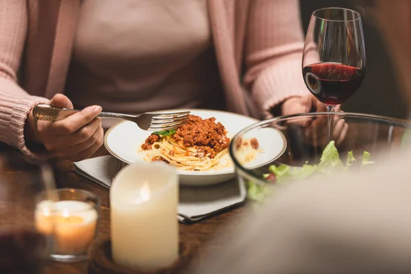 Vue recadrée de la femme assise à table et mangeant des pâtes pendant le dîner — Photo de stock