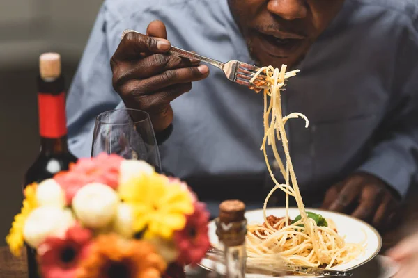 Vue recadrée de l'homme afro-américain mangeant des pâtes pendant le dîner — Photo de stock