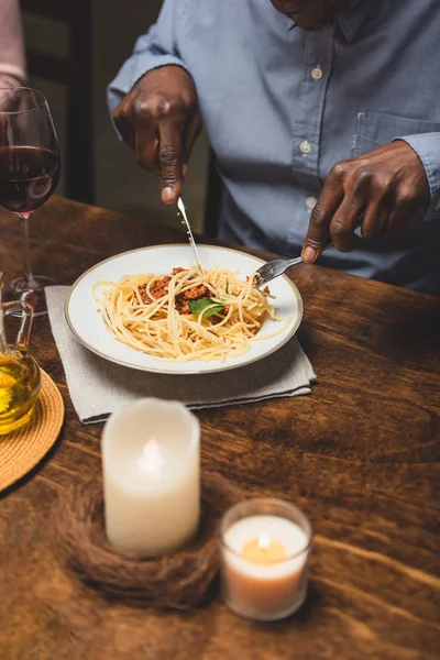 Vista cortada do homem americano africano comendo massa durante o jantar — Fotografia de Stock