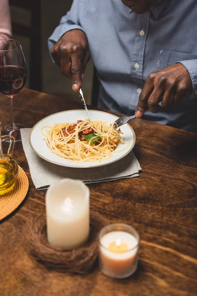 Vue recadrée de l'homme afro-américain mangeant des pâtes pendant le dîner — Photo de stock