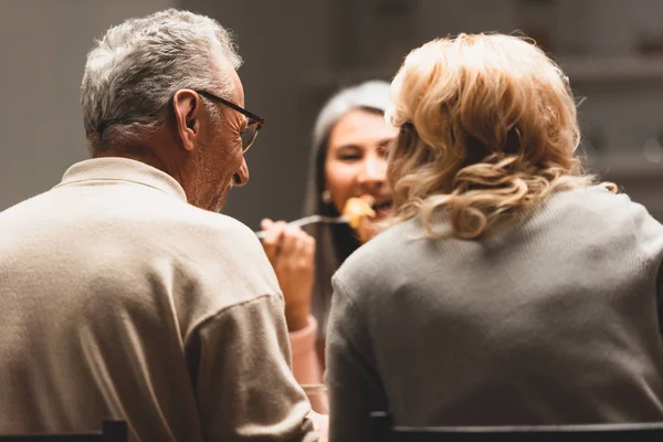 Back view of man and woman talking with smiling asian friend during dinner — Stock Photo