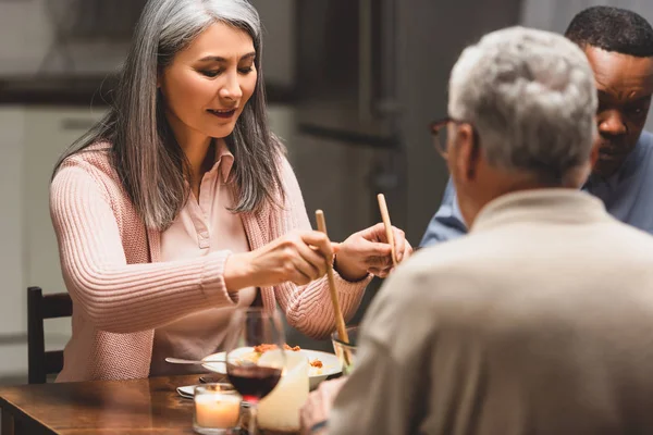 Selective focus of multicultural friends talking during dinner — Stock Photo