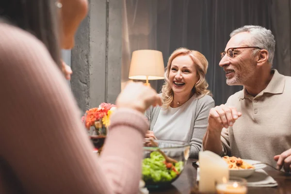 Enfoque selectivo de sonreír hombre y mujer hablando con un amigo durante la cena - foto de stock