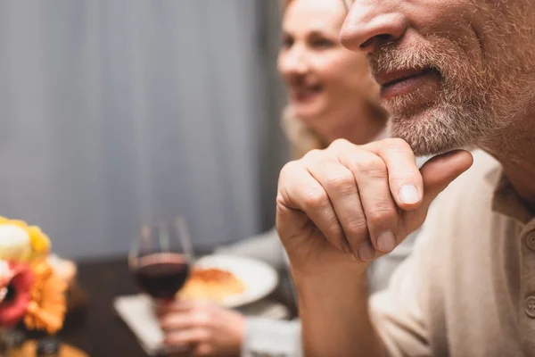 Vista ritagliata di uomo e donna sorridente sullo sfondo durante la cena — Foto stock