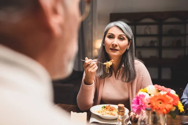 Selektiver Fokus einer Frau, die Pasta isst und ihre Freundin beim Abendessen ansieht — Stockfoto