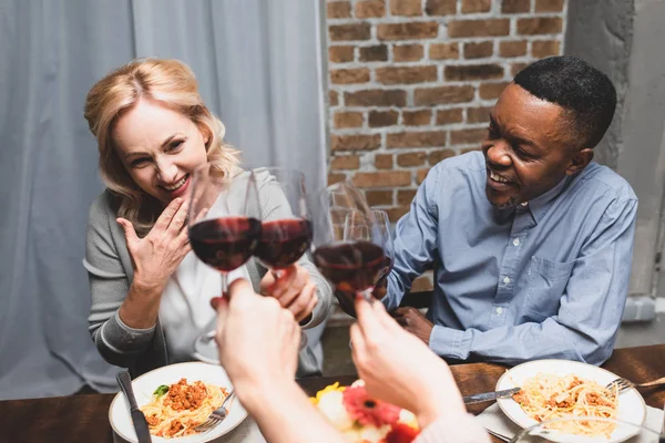 Vista cortada de amigos clinking com mulher caucasiana e homem americano africano durante o jantar — Fotografia de Stock