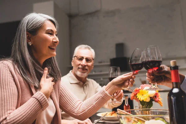 Abgeschnittene Ansicht eines afrikanisch-amerikanischen Mannes, der während des Abendessens mit einer lächelnden asiatischen Frau klirrt — Stockfoto