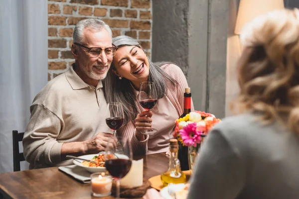 Selektiver Fokus lächelnder multikultureller Freunde mit Weingläsern beim Abendessen — Stockfoto