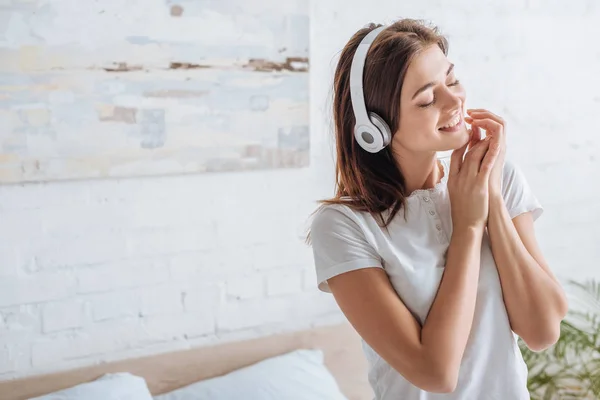 Весела жінка з закритими очима посміхається і слухає музику вдома — стокове фото