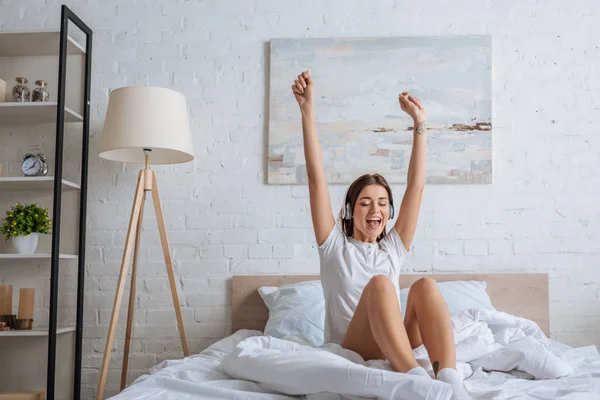 Glückliche Frau mit ausgestreckten Händen beim Musikhören im Schlafzimmer — Stockfoto