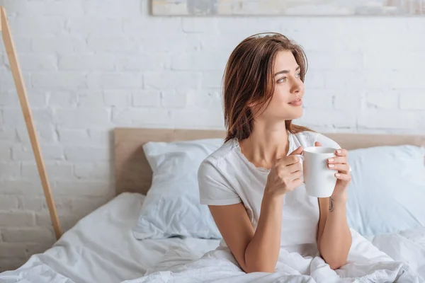 Felice giovane donna in possesso di tazza di tè in camera da letto — Foto stock