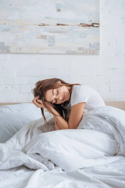 Mulher sorridente com os olhos fechados descansando na cama — Fotografia de Stock