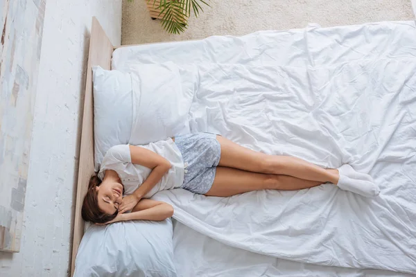 Vue de dessus de jeune belle femme en chaussettes se détendre tout en étant couché sur le lit — Photo de stock