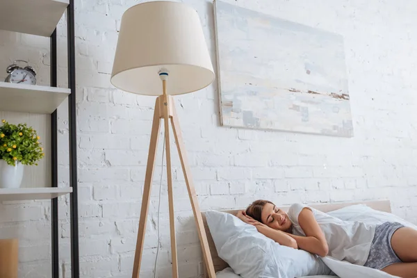 Jovem mulher bonita com olhos fechados relaxante enquanto deitado na cama — Fotografia de Stock