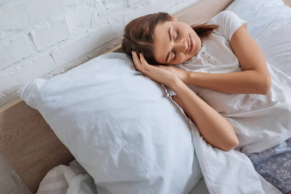 Jeune femme souriante se détendre tout en étant couché sur le lit — Photo de stock