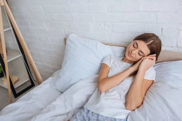 Atractiva mujer soñando mientras está acostada en la cama en casa - foto de stock