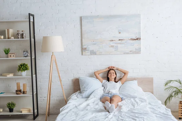Щаслива жінка з татуюванням лежить під час відпочинку в спальні — стокове фото