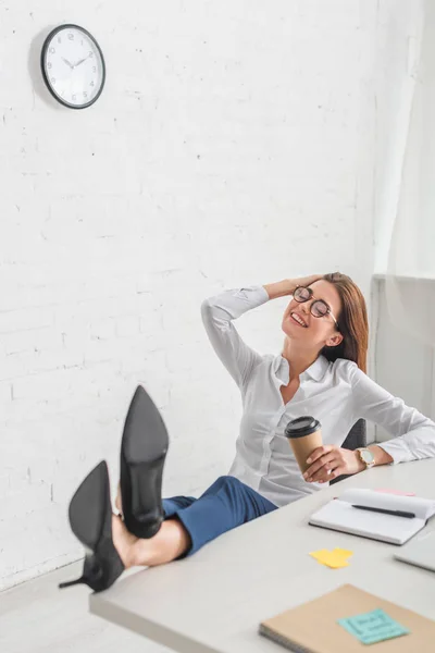 Enfoque selectivo de la mujer de negocios feliz sosteniendo taza de papel mientras se enfría en la oficina - foto de stock