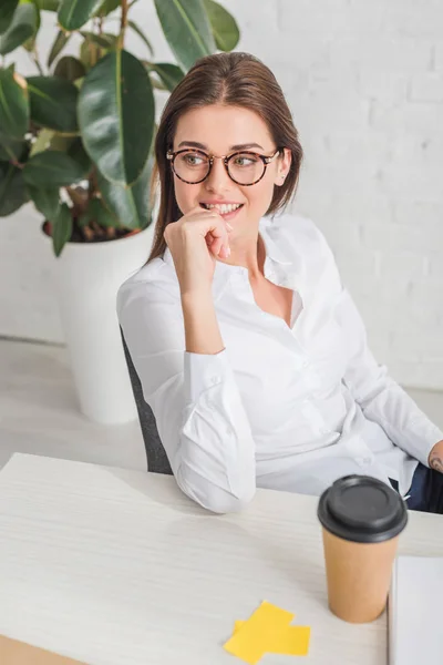 Hermosa mujer de negocios soñando cerca de taza de papel en la oficina - foto de stock