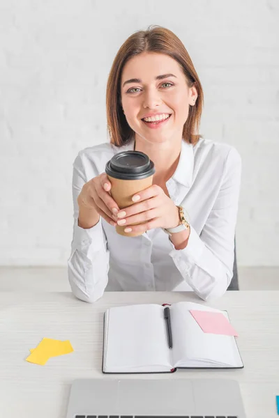 Щаслива бізнес-леді дивиться на камеру і тримає паперовий стаканчик — стокове фото