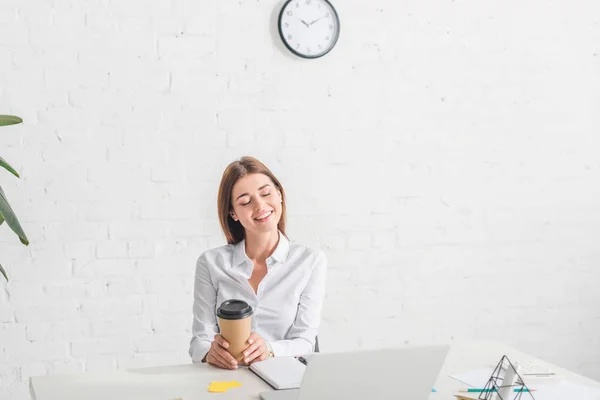 Счастливая деловая женщина охлаждения и проведения бумажной чашки в офисе — стоковое фото