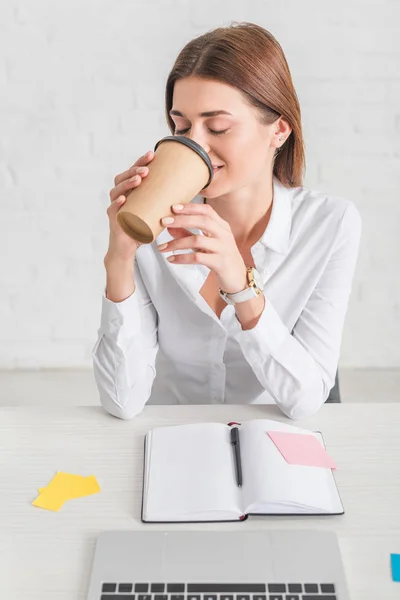 Счастливая бизнесвумен чилит и пьет кофе, чтобы пойти — стоковое фото