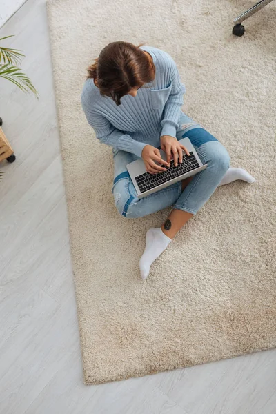 Верхний вид блоггера с помощью ноутбука, сидя на ковре — стоковое фото