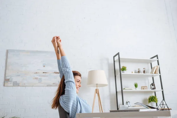 Felice ragazza agghiacciante e stretching vicino al tavolo a casa — Foto stock