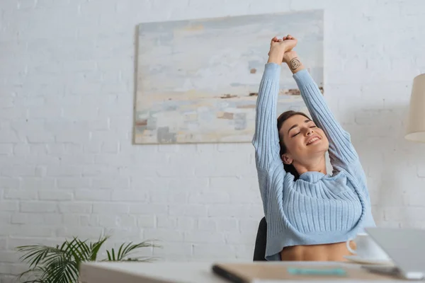 Selective focus of dreamy girl stretching near table at home — Stock Photo